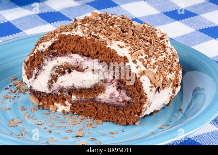 Il cioccolato rotolo svizzero torta con marmellata di frutti di bosco e panna montata su un fondo a scacchi Foto Stock