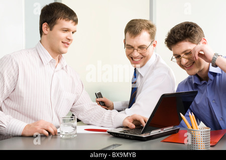 Team di tre uomini felici a discutere il loro progetto di business Foto Stock