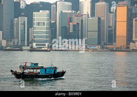 Sampan voce attraverso il Victoria Harbour in mattinata con la skyline di Kowloon in background, Isola di Hong Kong, Cina Foto Stock