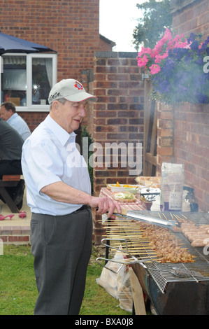 Anziani uomo bianco cuochi sul grande giardino barbecue Foto Stock