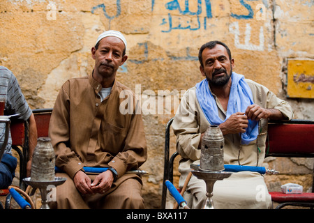 Due uomini egiziano godendo di fumare shisha in un tradizionale outdoor street cafe nella vita quotidiana del Cairo Islamico Foto Stock