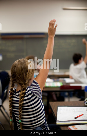 Gli studenti alzare le loro mani per rispondere alla domanda in studi sociali di classe a Kealing Middle School di Austin, Texas Foto Stock