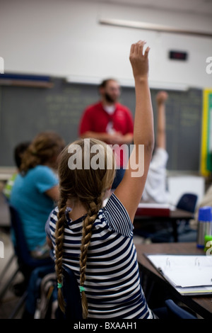 Gli studenti alzare le loro mani per rispondere alla domanda in studi sociali di classe a Kealing Middle School di Austin, Texas Foto Stock