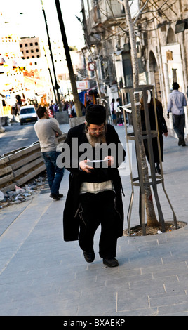 Passeggiate a piedi e a studiare la Bibbia allo stesso tempo. scena quotidiana nel centro di Gerusalemme. Foto Stock