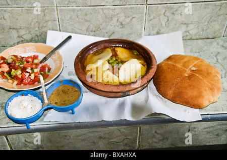 Marocchini mangiare loro Tajine con sale e cumino in polvere insieme con il pane appena sfornato. Foto Stock