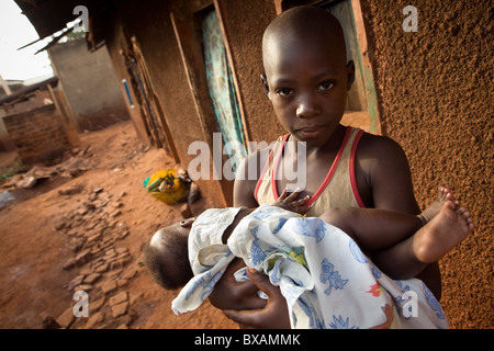 Un giovane ragazzo tiene un bambino in una delle baraccopoli in Jinja, Uganda, Africa orientale. Foto Stock