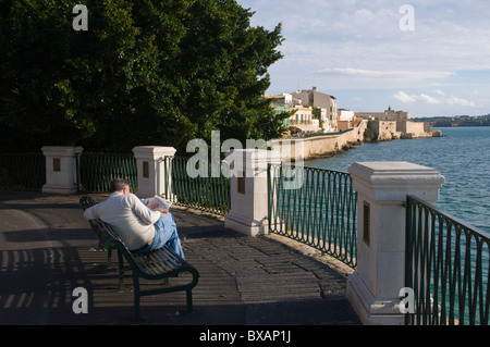 Uomo che legge il giornale a Largo Aretusa square nell isola di Ortigia città vecchia Siracusa Sicilia Italia Europa Foto Stock