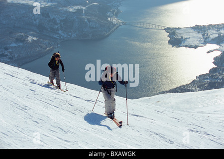 Due persone telemark nel paesaggio invernale, Lago di Mjosa in background Foto Stock