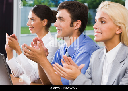 Tre uomini di affari che applaudire dopo la fine del parlato a un seminario Foto Stock