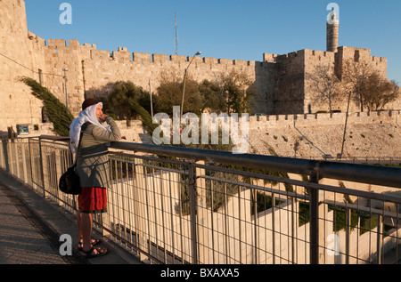 Uomo in orientali vestiti esotici in piedi alla Porta di Jaffa con la cittadella di Davide in bkgd Foto Stock