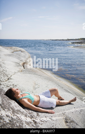 Donna sdraiata sulla roccia Foto Stock