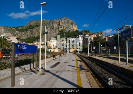 Cefalu centrale la principale stazione ferroviaria di piattaforme con la rocca in background storico cefalu Sicilia Italia Europa Foto Stock