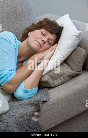 Donna matura che dorme sul divano Foto Stock