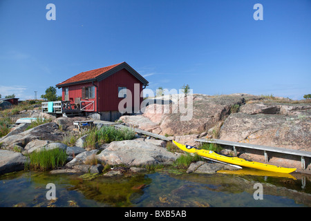 Giallo canoa ormeggiata accanto alla piccola casa cottage Foto Stock