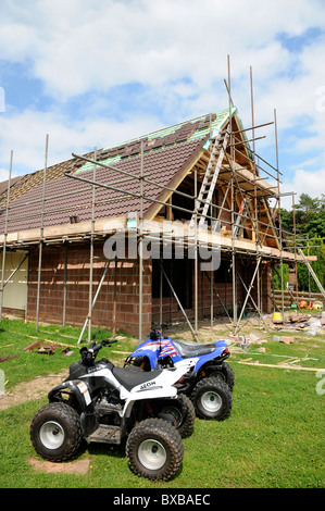 Una casa in procinto di essere esteso con due processori quad bike nel giardino del Galles, Regno Unito Foto Stock
