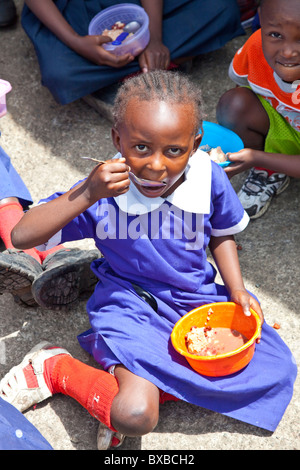 Ragazza a mangiare cibo fornito a Maji Mazuri scuola nella baraccopoli di Mathare, Nairobi, Kenia Foto Stock