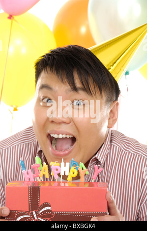 Uomo con un regalo di compleanno e sorridente Foto Stock