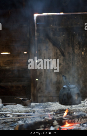 Il caffè in un tradizionale modo finlandese su un fuoco di campo in un pieno di fumo capanna. Le pareti sono scuri dal fumo Foto Stock