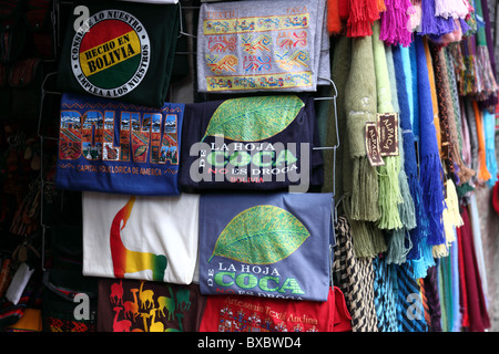 'La foglia di coca non è una droga" T-shirt e lana di alpaca sciarpe per la vendita al di fuori del negozio nel mercato del turismo, La Paz, Bolivia Foto Stock