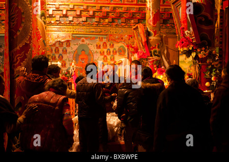 Un monaco tibetano benedice lamaist aderenti durante una cerimonia nel tempio Tagong, nella provincia di Sichuan, in Cina Foto Stock