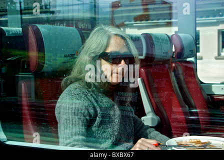 La donna attraverso il vetro del finestrino seduti all'interno della rampa panoramica auto a bordo Matterhorn Gotthard Bahn treno Glacier Express in stazione Foto Stock