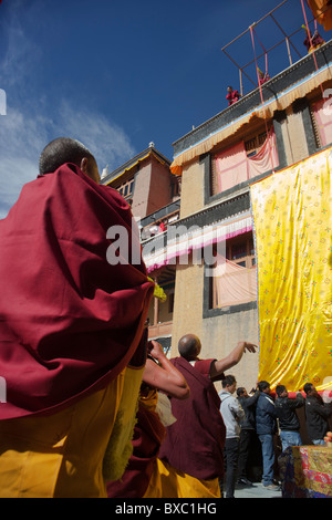 I monaci arrotolamento di un gigantesco thangka e portandolo su off per la memorizzazione Foto Stock