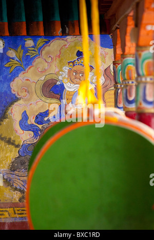 Tamburi di preghiera appeso davanti a una parete buddista pittura presso il monastero di Thiksey in Ladakh Foto Stock