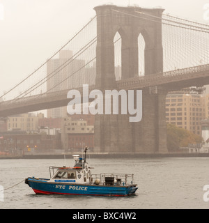 Barca NYPD sull'East River con il ponte di Brooklyn a Manhattan, New York City, U.S.A. Foto Stock