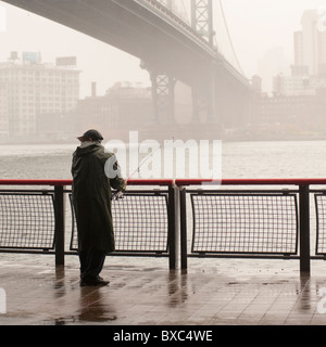 L'uomo pesca sull'East River shore a Manhattan, New York City, U.S.A. Foto Stock