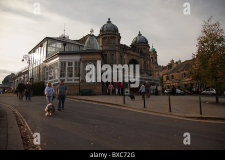 Due persone a piedi un cane fuori Buxton Pavilion Gardens Buxton Peak District Derbyshire England Regno Unito Foto Stock