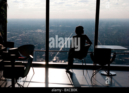 Donna seduta dalla finestra a Chicago, John Hancock Center Foto Stock