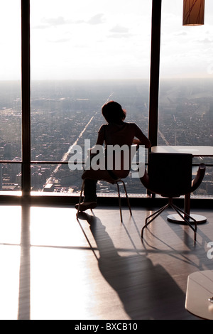 Donna seduta dalla finestra a Chicago, John Hancock Center Foto Stock