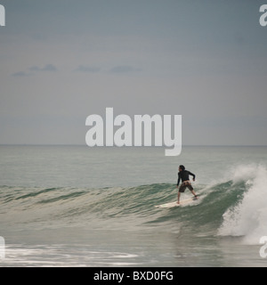 Surfer riging un'onda lungo Costa Rica seashore Foto Stock