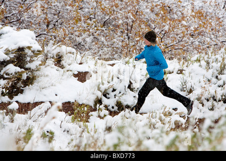 Una donna trail running dopo una leggera nevicata. Foto Stock