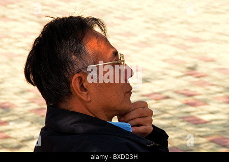 Uomo asiatico seduto su una panchina nel parco di Hong Kong Cina Foto Stock