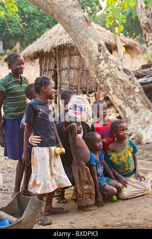 Donna bionda visitatore pone con bambini nativi in Kawaza village, Zambia, Africa. Queste persone sono di Kunda tribù. Foto Stock