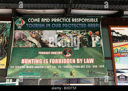 Accedi in lingua inglese incoraggiando il turismo responsabile e dichiarando che la caccia è vietata dalla legge nel terminal dell'aeroporto, Rurrenabaque, Bolivia Foto Stock