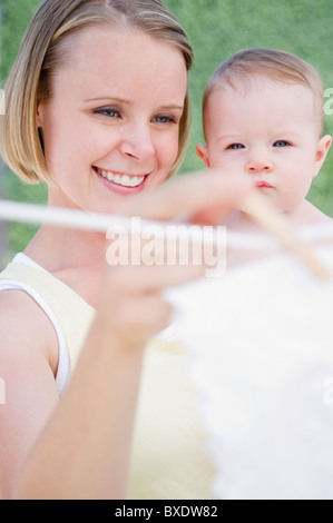 Azienda madre bambino mentre appendere il bucato Foto Stock