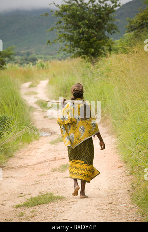 Un contadino cammina per un villaggio lane al di fuori di Iringa, Tanzania Africa Orientale. Foto Stock