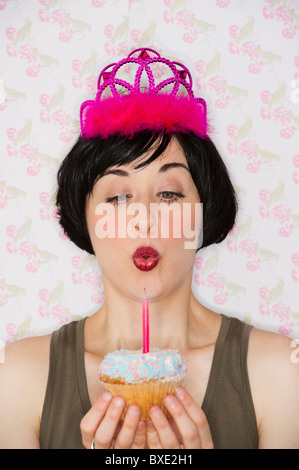 Compleanno ragazza soffiando fuori candela sul cupcake Foto Stock