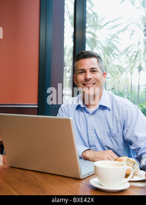 Uomo al lavoro su laptop in ristorante Foto Stock