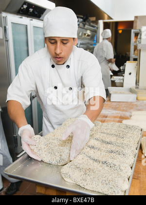 Lo Chef rendendo il pane nel forno Foto Stock