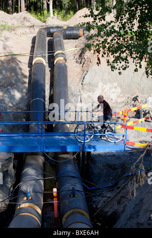 Biker che attraversa un ponte temporaneo sulla conduttura sotterranea di riscaldamento urbano in costruzione , Finlandia Foto Stock