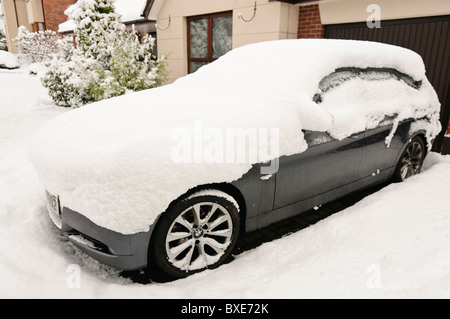 Coperta di neve vettura bloccato su un viale di accesso al di fuori di una casa Foto Stock