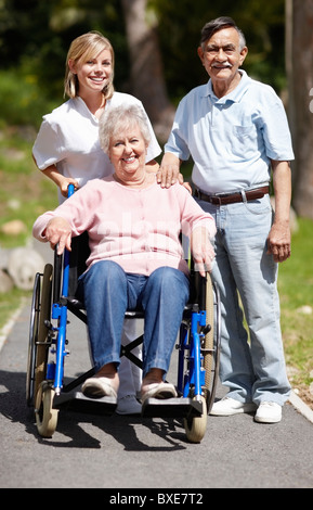 Infermiere spingendo senior donna in una sedia a rotelle Foto Stock