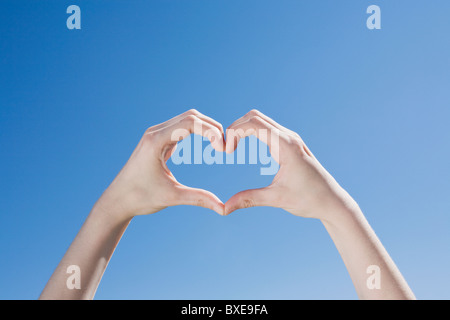 Mani formando una forma di cuore Foto Stock