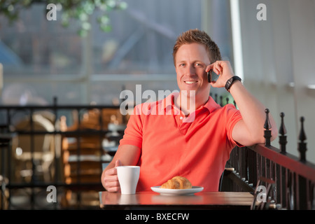 Uomo seduto sul patio al cafe Foto Stock