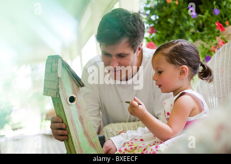 Aiutando il padre di sua figlia dipingere un birdhouse Foto Stock