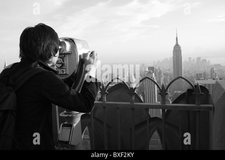 Un uomo guarda attraverso un telescopio da Rockefeller Center di Manhattan inferiore Foto Stock