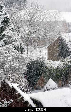 Vista di case e giardini in una pesante nevicata invernale e blizzard meteo Foto Stock